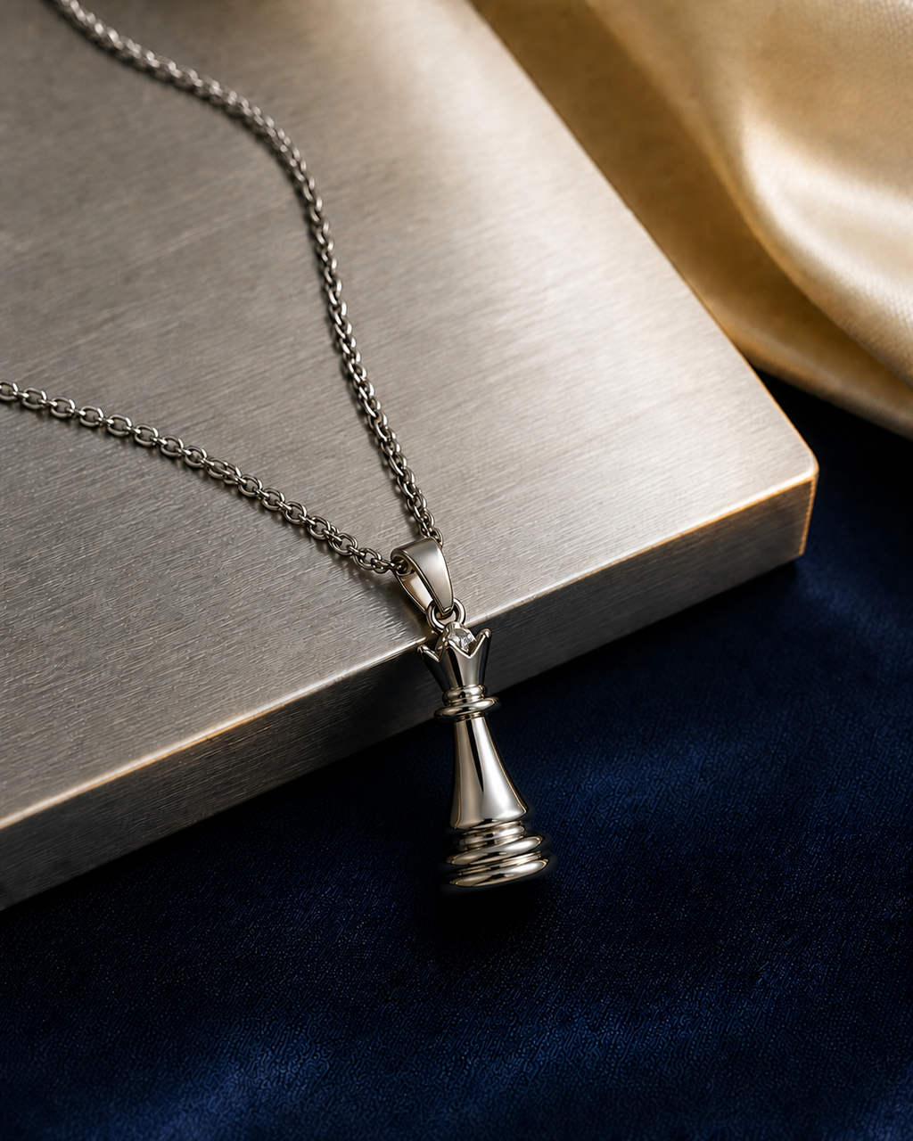 Silver-tone Queen Necklace beside precision-brushed stainless steel in a navy and cream editorial setting.